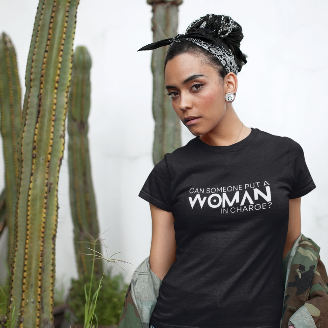 Woman wearing a black tshirt that says, "Can Someone Put A Woman in Charge?" Every purchase donates to Equality Now.