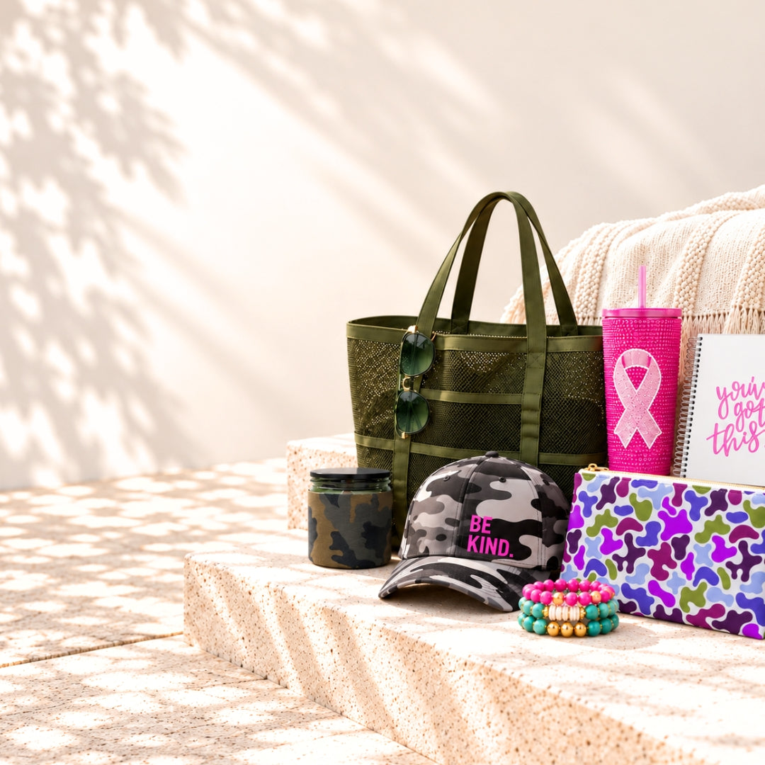Purpose-driven gifts supporting U.S.VETS and breast cancer awareness, including a camo tote, Be Kind hat, pink ribbon tumbler, bracelets, clutch and journal.