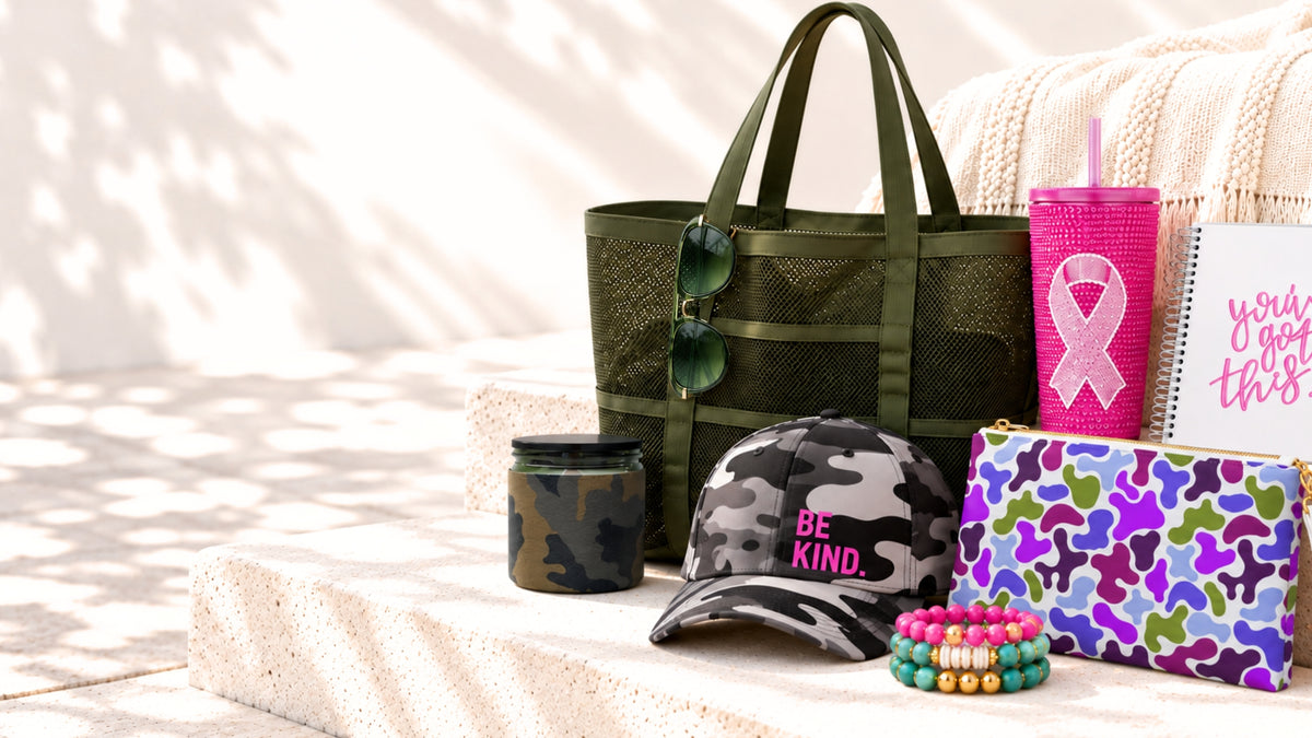 Purpose-driven gifts supporting U.S.VETS and breast cancer awareness, including a camo tote, Be Kind hat, pink ribbon tumbler, bracelets, clutch and journal.